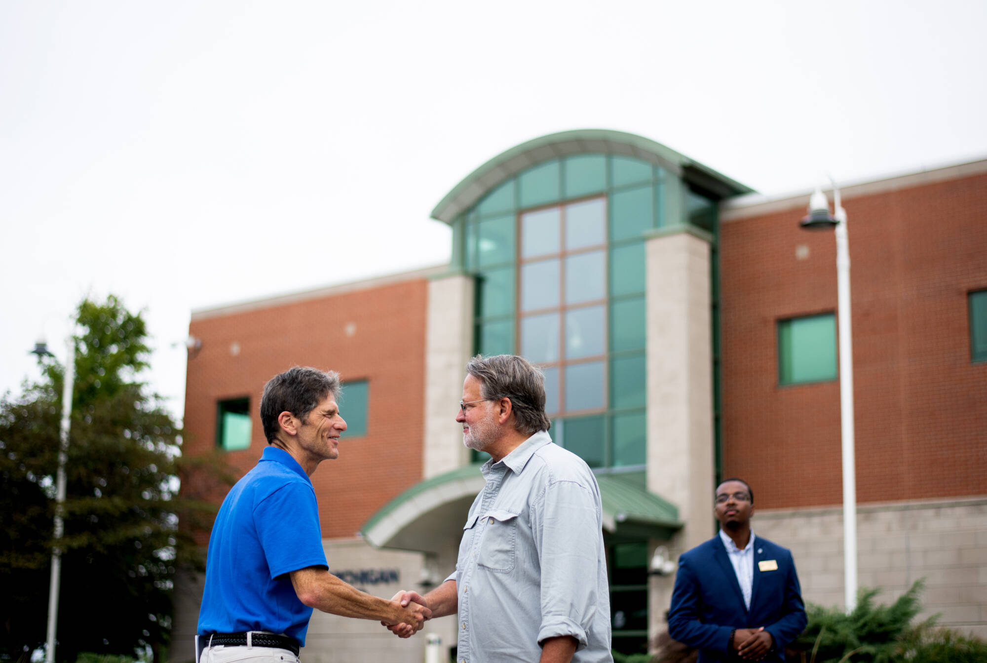 Al Steinman, Allen and Helen Hunting Research Professor, left, shakes hands with U.S. Senator Gary Peters, right, in front of GVSU’s Lake Michigan Center as Peters starts his motorcycle tour August 29.
